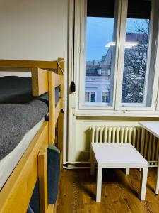 a room with a bed and a table and two windows at Hostel Stari Grad in Novi Sad