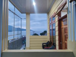 - un balcon avec deux chaises et une vue sur l'eau dans l'établissement Tama View, à Tuk Tuk
