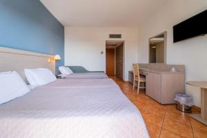 a hotel room with two beds and a desk at Oceanis Hotel in Kavála