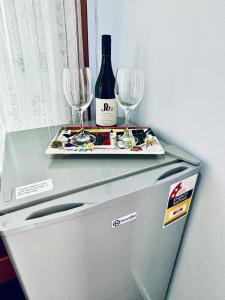 Kelvin Garden Villa في كوينزتاون: زجاجة من النبيذ وكأسين فوق الثلاجة