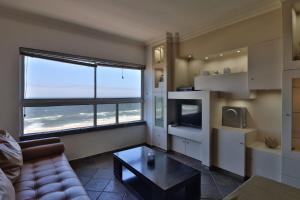 a living room with a couch and a large window at 604@Amanzi 2-bedroom holiday apartment by the sea in Amanzimtoti