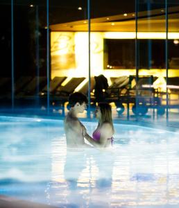 a man and a woman standing in a swimming pool at Lido Palace - The Leading Hotels of the World in Riva del Garda