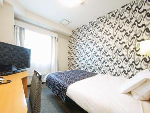 um quarto de hotel com uma cama e uma televisão em APA Hotel Kanku-Kishiwada em Kishiwada