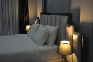 1 dormitorio con 1 cama con almohadas blancas y lámpara en Dreams Inn Luxury Residences & Lifestyle, en Cimenli