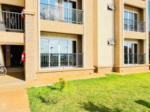 a building with balconies and a lawn in front of it at 3 bedroom apartment in Mirembe Villas Kigo, Kampala, Entebbe Uganda in Kigo