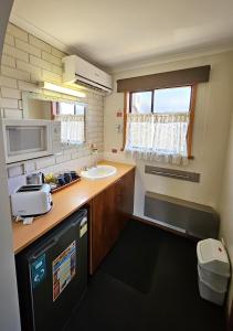 una pequeña cocina con fregadero y microondas en Alfred Motor Inn, en Ballarat