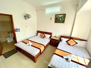 a hotel room with two beds and a bathroom at Ngoc dung MoTel in Vung Tau