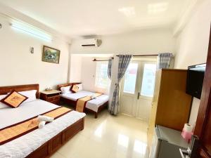a room with two beds and a couch and a tv at Ngoc dung MoTel in Vung Tau