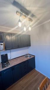 a kitchen with blue cabinets and a sink and lights at Obolonskiy Prospekt Apartments 16Є in Kyiv