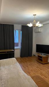 a bedroom with a bed and a flat screen tv at Obolonskiy Prospekt Apartments 16Є in Kyiv