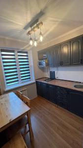 a kitchen with black cabinets and a wooden table at Obolonskiy Prospekt Apartments 16Є in Kyiv