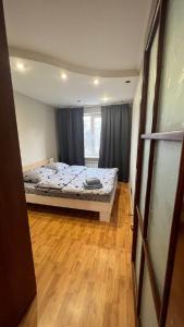 a bedroom with a bed and a wooden floor at Obolonskiy Prospekt Apartments 16Є in Kyiv