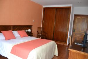a bedroom with a bed and a desk with a television at Hotel Rural Ibipozo in El Almicerán