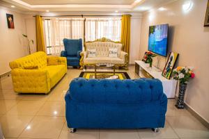 a living room with a blue couch and yellow chairs at Dylan Shawmutt Luxurious 3 Bedroom Apartment in Nakuru