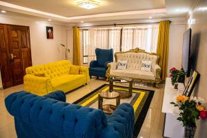 a living room with blue couches and a yellow couch at Dylan Shawmutt Luxurious 3 Bedroom Apartment in Nakuru