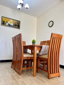 a dining room table with chairs and a clock on the wall at 3 bedroom apartment in Mirembe Villas Kigo, Kampala, Entebbe Uganda in Kigo