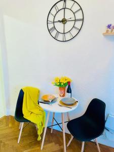 a table with two chairs and a clock on a wall at Central studio AC & balcony in Nice
