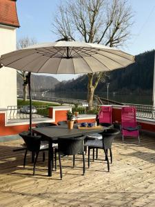 una mesa y sillas bajo una sombrilla en un patio en Terrassenwohnung mit Donaublick, en Obernzell