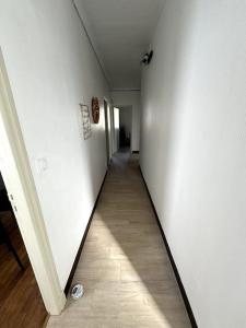 a hallway with white walls and a wooden floor at Appartement Sabatier T4 avec terrasse et jardin in Carcassonne