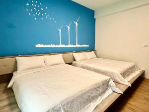 two beds in a room with windmills on the wall at 澎湖菊舍民宿一館 in Magong