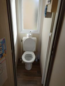 a small bathroom with a toilet with a window at CAMPING L’ELYSÉE *** in Le Grau-du-Roi
