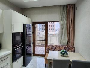 a living room with a table and a kitchen with a window at Park Azure Best apartment in Baku