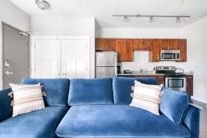 a blue couch in a living room with a kitchen at CozySuites Music Row Bold 1BR w free parking in Nashville