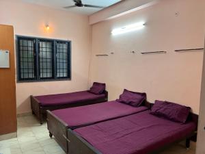 two beds in a room with purple sheets at M K Raja Hotel in Kelambākkam