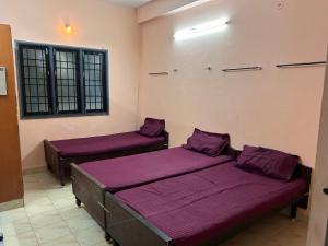 two beds in a room with purple sheets at M K Raja Hotel in Kelambākkam