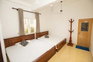 a bedroom with two beds and a cross on the wall at Ama Residency & Homestay Kandy in Hindagala