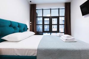 a bedroom with a bed with a blue headboard and a window at Апартаменти на Кирилівська 37 in Kyiv