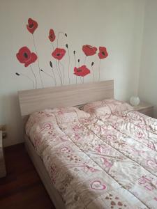 een slaapkamer met een bed met rode bloemen aan de muur bij La Casa di Boh, vicino ospedale San Paolo, Iulm, Forum Assago in Milaan