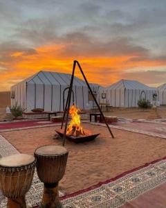 a fire pit in the middle of a desert with tents at Luxury Desert Camp Merzouga in Merzouga