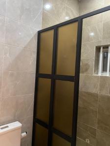 uma porta de chuveiro numa casa de banho com WC em Residence SIRTAK em Cotonou