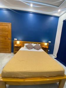 um quarto com uma cama grande e uma parede azul em Residence SIRTAK em Cotonou