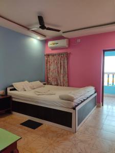 een bed in een kamer met een roze muur bij Hotel Mainak Mandarmani in Mandarmoni