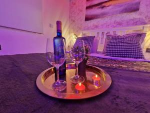 Una bandeja con dos copas de vino, una botella y una vela. en sensual sierra love, en Prado del Rey