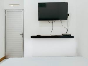 una TV a schermo piatto appesa a un muro bianco di Eleven Guest House Syariah a Sukaraja