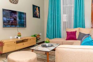 a living room with a couch and a tv at Family Friendly 2-BR Apartment Near Mlimani City in Dar es Salaam