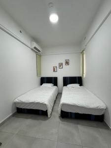two beds in a room with white walls at Sandakan Blue Coastal escape 蓝海岩栖 in Sandakan