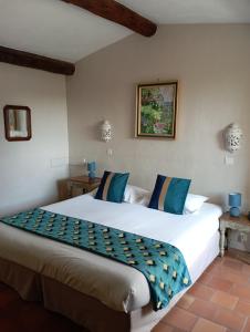 a bedroom with a large white bed with blue pillows at Hotel Mas De Cure Bourse in L'Isle-sur-la-Sorgue