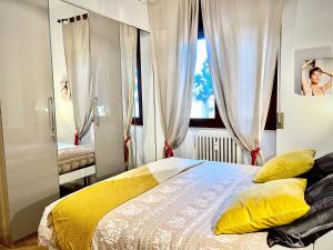 Un dormitorio con una cama con almohadas amarillas y una ventana. en Gallery Fiera Milano, en Cornaredo