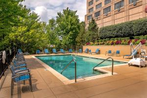 una piscina con sillas azules y un edificio en Marriott St. Louis West, en Chesterfield
