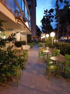 un patio esterno con tavoli e sedie di notte di Hotel Konrad a Rimini