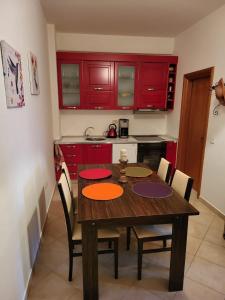 a kitchen with a wooden table and red cabinets at Little Pearl in Orikum +3 photos