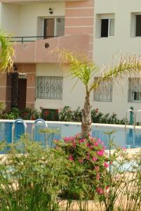 a house with a palm tree and flowers in front of it at Mohammedia Plage et piscines in Mohammedia