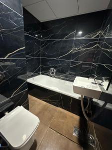a bathroom with a toilet and a sink and a tub at Hotel Dumas Near Airport in Surat