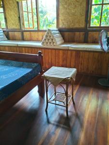 um quarto com uma cama, uma cadeira e janelas em eco beach house bali em Penginuman