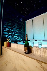 濱海拉塞訥的住宿－Flower Suite and Spa，柜台上的一瓶葡萄酒和两杯酒