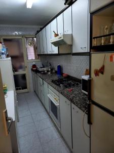 La cuisine est équipée de placards blancs et d'un four avec plaques de cuisson. dans l'établissement Piso para compartir, à Santa Coloma de Gramanet